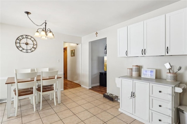 kitchen with pendant lighting, white cabinets, a chandelier, and light tile patterned floors