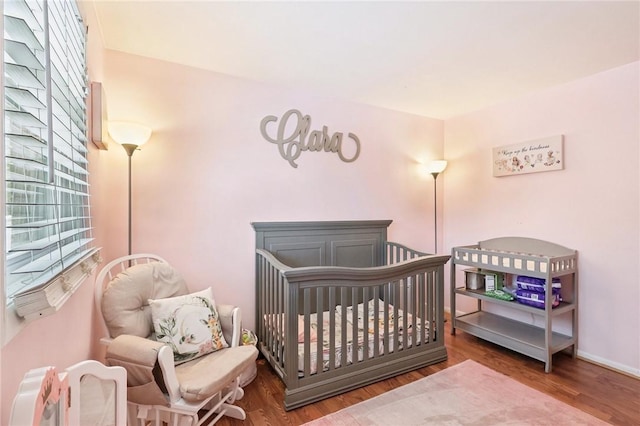 bedroom featuring a nursery area and hardwood / wood-style floors