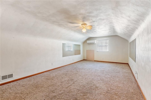 additional living space with ceiling fan, carpet floors, a wall mounted AC, and vaulted ceiling