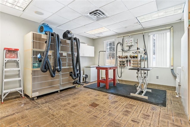 workout room with a paneled ceiling and a healthy amount of sunlight