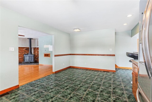 316 Noll Rd, Hanover Twp Bea, PA 15043 - empty room with a wood stove, wood finished floors, and baseboards