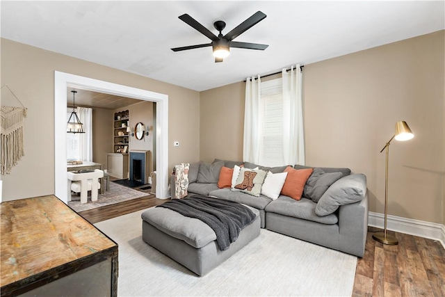 living room featuring ceiling fan with notable chandelier and hardwood / wood-style floors