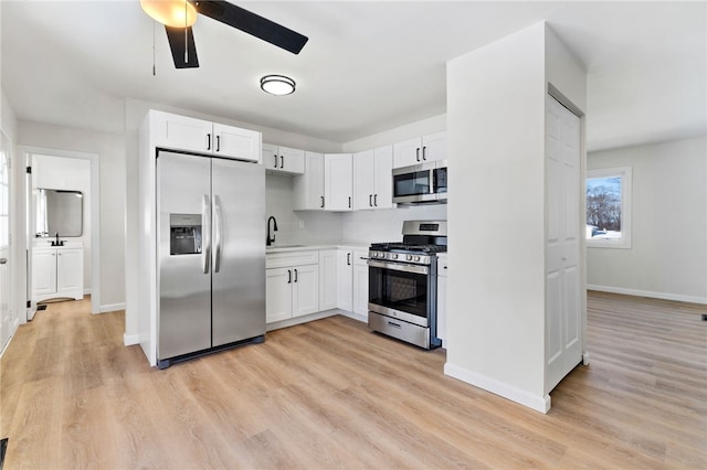 kitchen with sink, white cabinetry, light wood-type flooring, appliances with stainless steel finishes, and ceiling fan