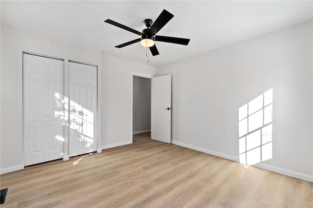 unfurnished bedroom featuring two closets, light hardwood / wood-style flooring, and ceiling fan