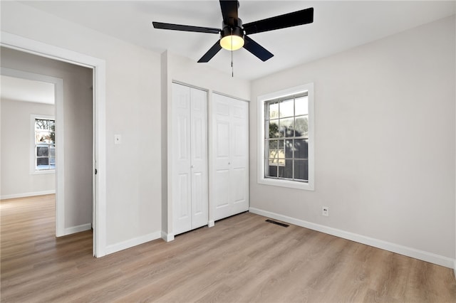 unfurnished bedroom featuring multiple windows, light wood-type flooring, and ceiling fan