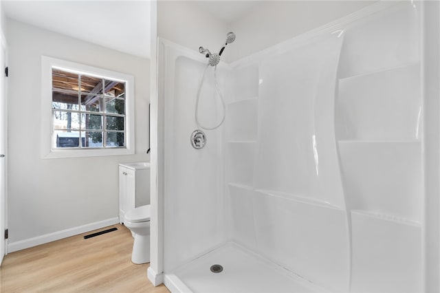 bathroom with wood-type flooring, a shower, and toilet