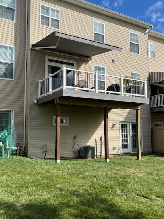 rear view of property featuring french doors, a yard, and central AC unit