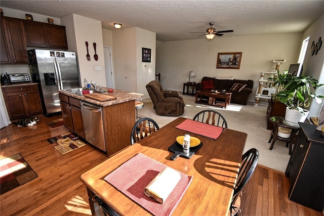 dining space with sink, dark hardwood / wood-style floors, a textured ceiling, and ceiling fan