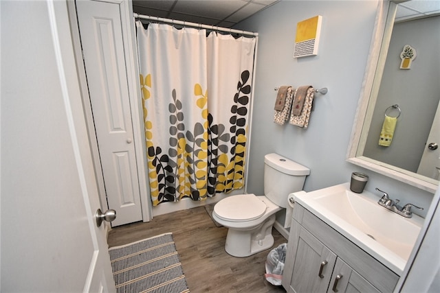 bathroom featuring walk in shower, toilet, a paneled ceiling, wood-type flooring, and vanity