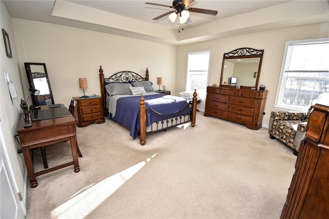 carpeted bedroom featuring ceiling fan and a tray ceiling