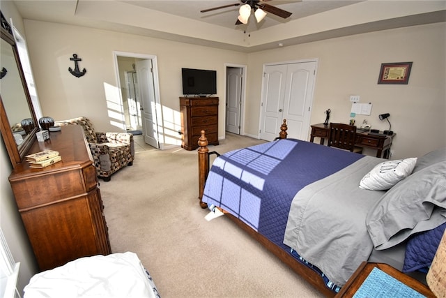 bedroom featuring a raised ceiling, light carpet, and ceiling fan