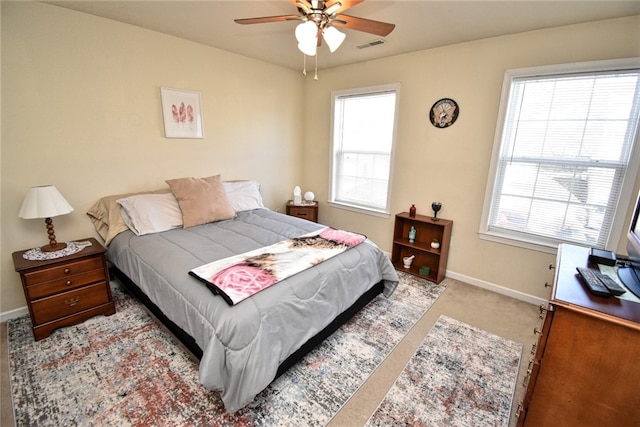 bedroom featuring ceiling fan, light carpet, and multiple windows