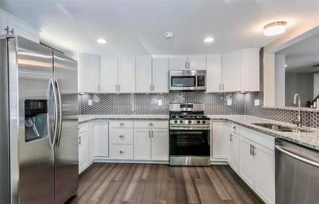 kitchen featuring sink, light stone counters, appliances with stainless steel finishes, decorative backsplash, and white cabinets