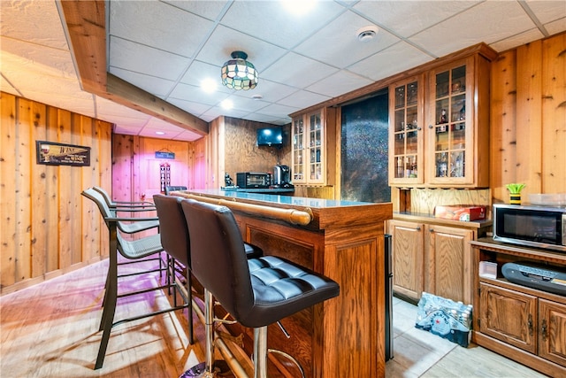 bar with a paneled ceiling and wood walls