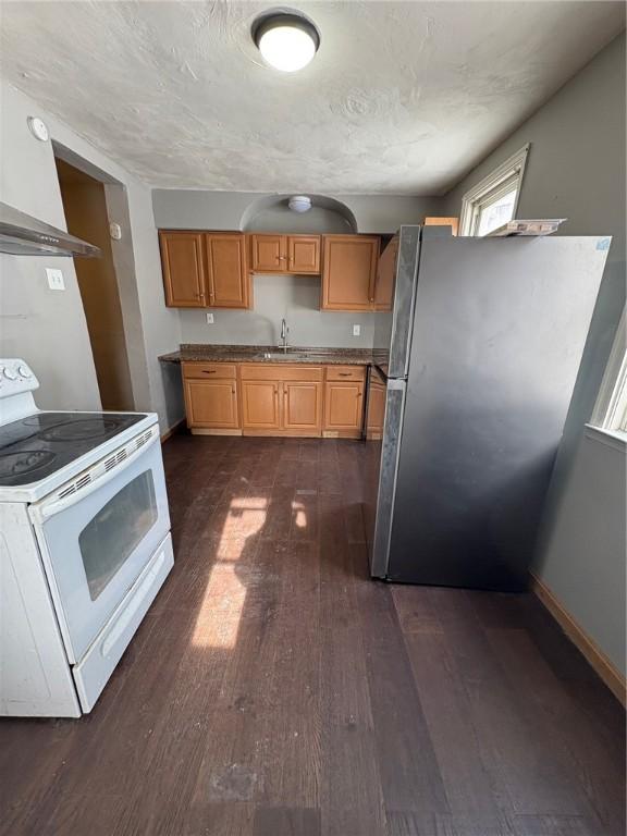 kitchen with sink, stainless steel refrigerator, white range with electric cooktop, dark hardwood / wood-style floors, and a textured ceiling