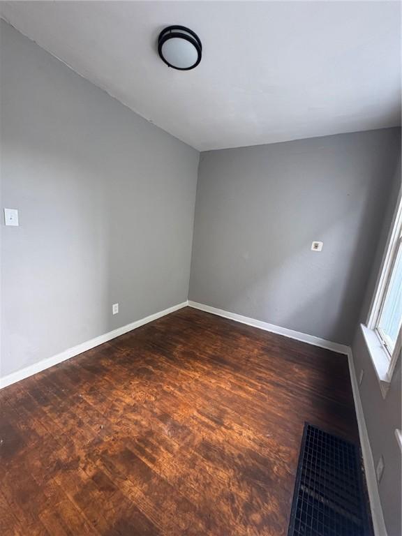 empty room with dark hardwood / wood-style flooring