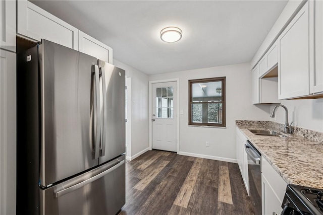 kitchen with sink, white cabinets, light stone counters, stainless steel appliances, and dark wood-type flooring