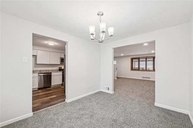 empty room featuring a chandelier and dark carpet