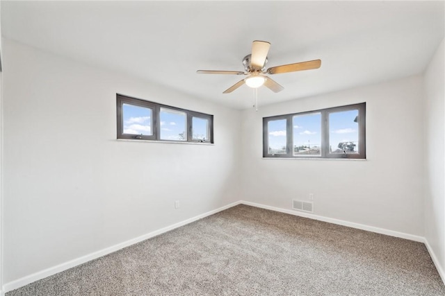 carpeted spare room featuring a wealth of natural light and ceiling fan