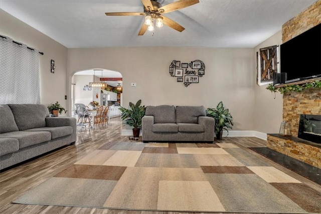 living room featuring ceiling fan, a fireplace, and light wood-type flooring