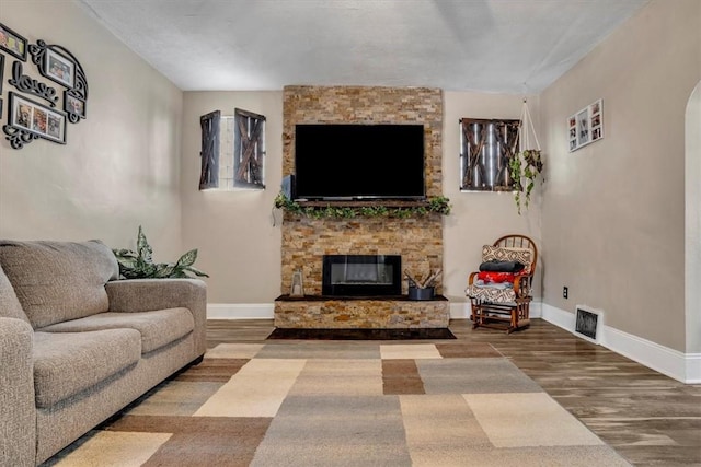 living room featuring a stone fireplace and hardwood / wood-style floors