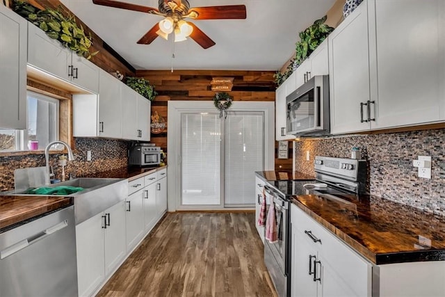 kitchen featuring tasteful backsplash, wood-type flooring, sink, white cabinets, and stainless steel appliances