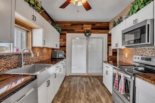 kitchen featuring sink, light hardwood / wood-style flooring, appliances with stainless steel finishes, white cabinets, and decorative backsplash