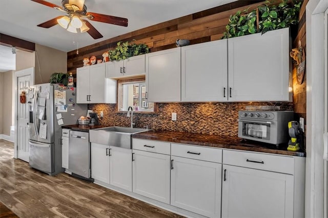 kitchen with sink, tasteful backsplash, wood-type flooring, appliances with stainless steel finishes, and white cabinets