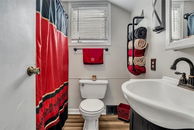 bathroom with lofted ceiling, toilet, sink, and hardwood / wood-style floors