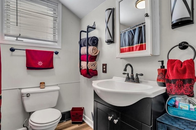 bathroom featuring vaulted ceiling, hardwood / wood-style floors, vanity, and toilet