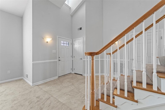 entrance foyer with light colored carpet, a skylight, and high vaulted ceiling