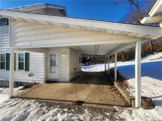 snow covered patio with a carport