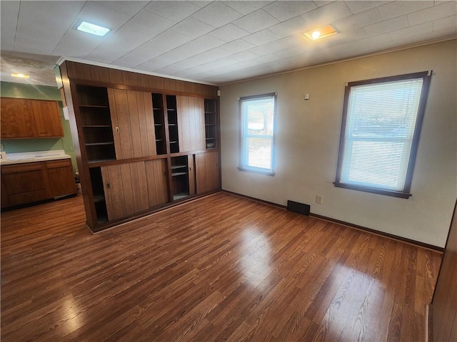 unfurnished living room with crown molding and dark wood-type flooring