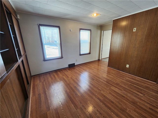 unfurnished room featuring crown molding, wood-type flooring, and wood walls