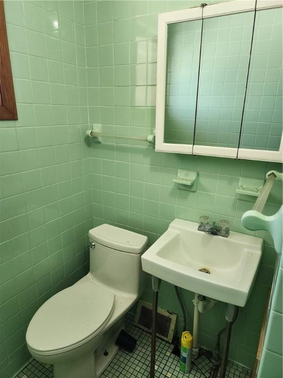 bathroom with tile patterned flooring, sink, tile walls, and toilet