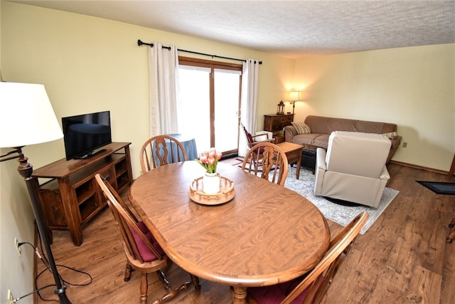 dining space featuring hardwood / wood-style floors and a textured ceiling