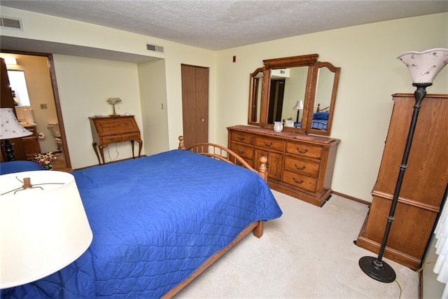 carpeted bedroom with ensuite bathroom and a textured ceiling