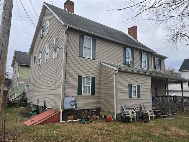 rear view of house featuring cooling unit and a lawn