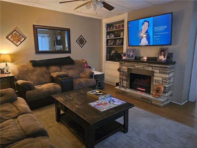 living room featuring ceiling fan, wood-type flooring, a fireplace, and built in features