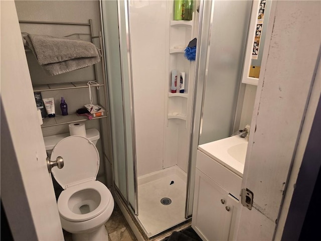 bathroom featuring a shower with door, vanity, tile patterned floors, and toilet