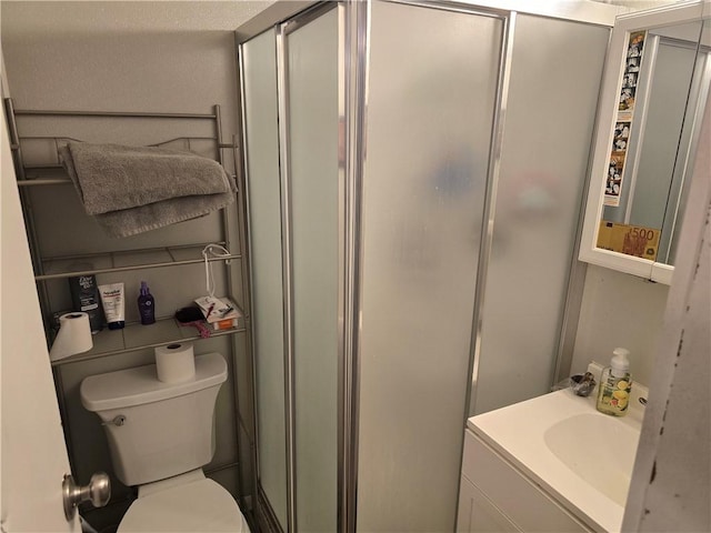 bathroom featuring toilet, vanity, and a shower with shower door