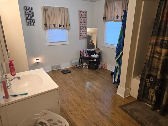 bathroom featuring hardwood / wood-style flooring, vanity, and shower / tub combo