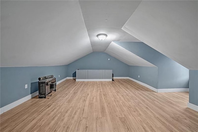 additional living space featuring lofted ceiling and light wood-type flooring