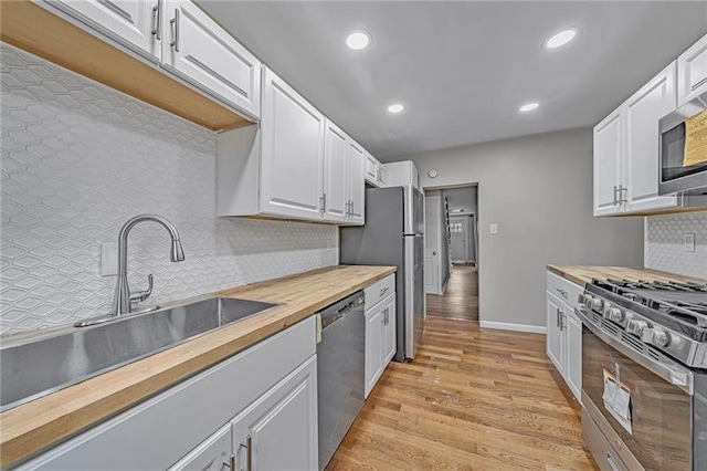 kitchen featuring a sink, wood counters, white cabinetry, light wood-style floors, and appliances with stainless steel finishes