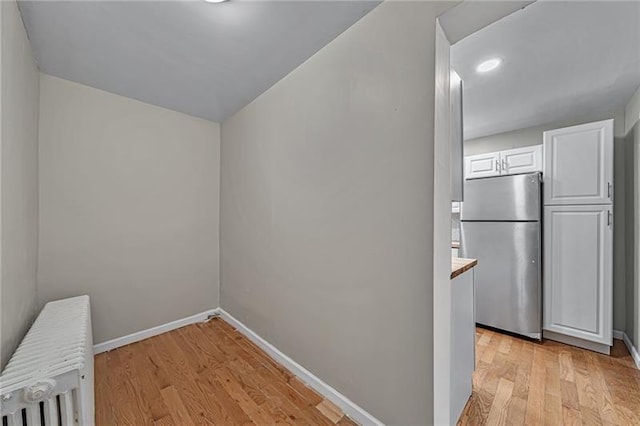 interior space with baseboards, radiator heating unit, and light wood-style floors