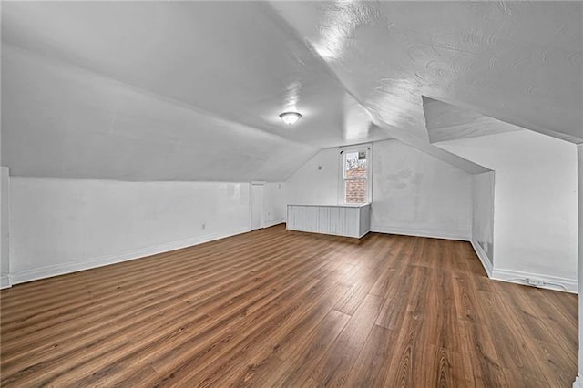 additional living space with vaulted ceiling, baseboards, and wood finished floors