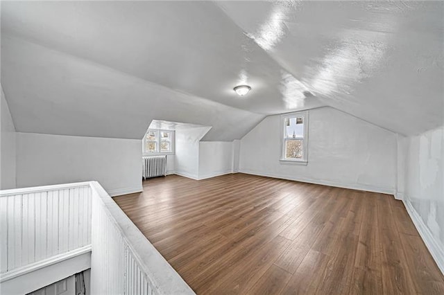 bonus room with radiator, baseboards, lofted ceiling, wood finished floors, and a textured ceiling