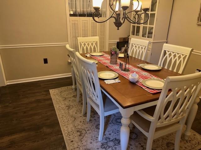 dining area featuring dark hardwood / wood-style flooring and an inviting chandelier