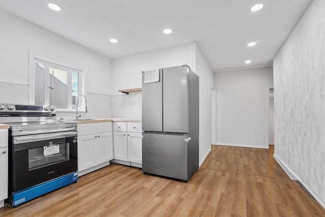 kitchen featuring sink, tasteful backsplash, appliances with stainless steel finishes, light hardwood / wood-style floors, and white cabinets