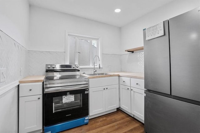 kitchen with sink, white cabinets, dark hardwood / wood-style flooring, decorative backsplash, and stainless steel appliances